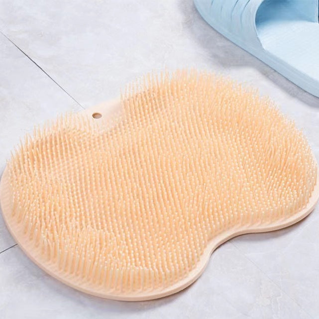 Orange bath brush on a tiled bathroom floor with a blue slipper in the background.