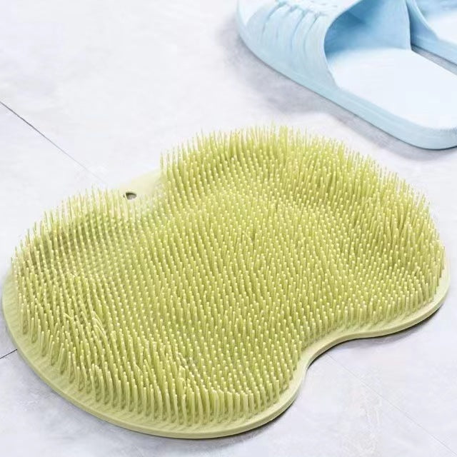 Green scrubbing brush on a tiled floor with a blue slipper in the background.